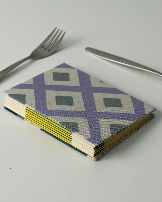 Ricettario formato A6, carta agrumi, rilegatura australiana, piastrelle colorate grigio, lilla e blu (rombi)