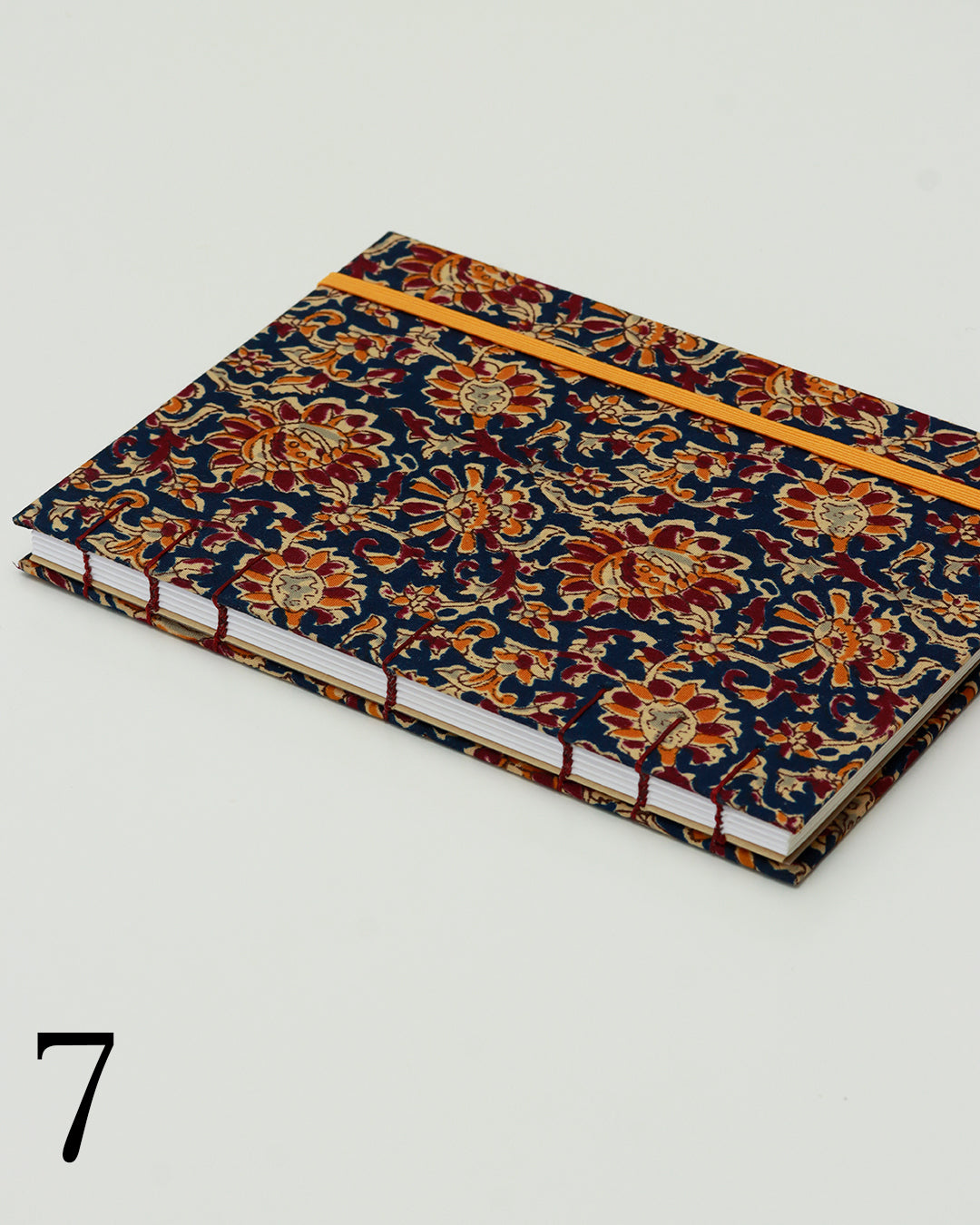 Quaderno per calligrafia con rilegatura copta, copertina in tessuto floreale block-print blu notte con motivi arancio, bordeaux e oro, elastico arancio, filo bordeaux
