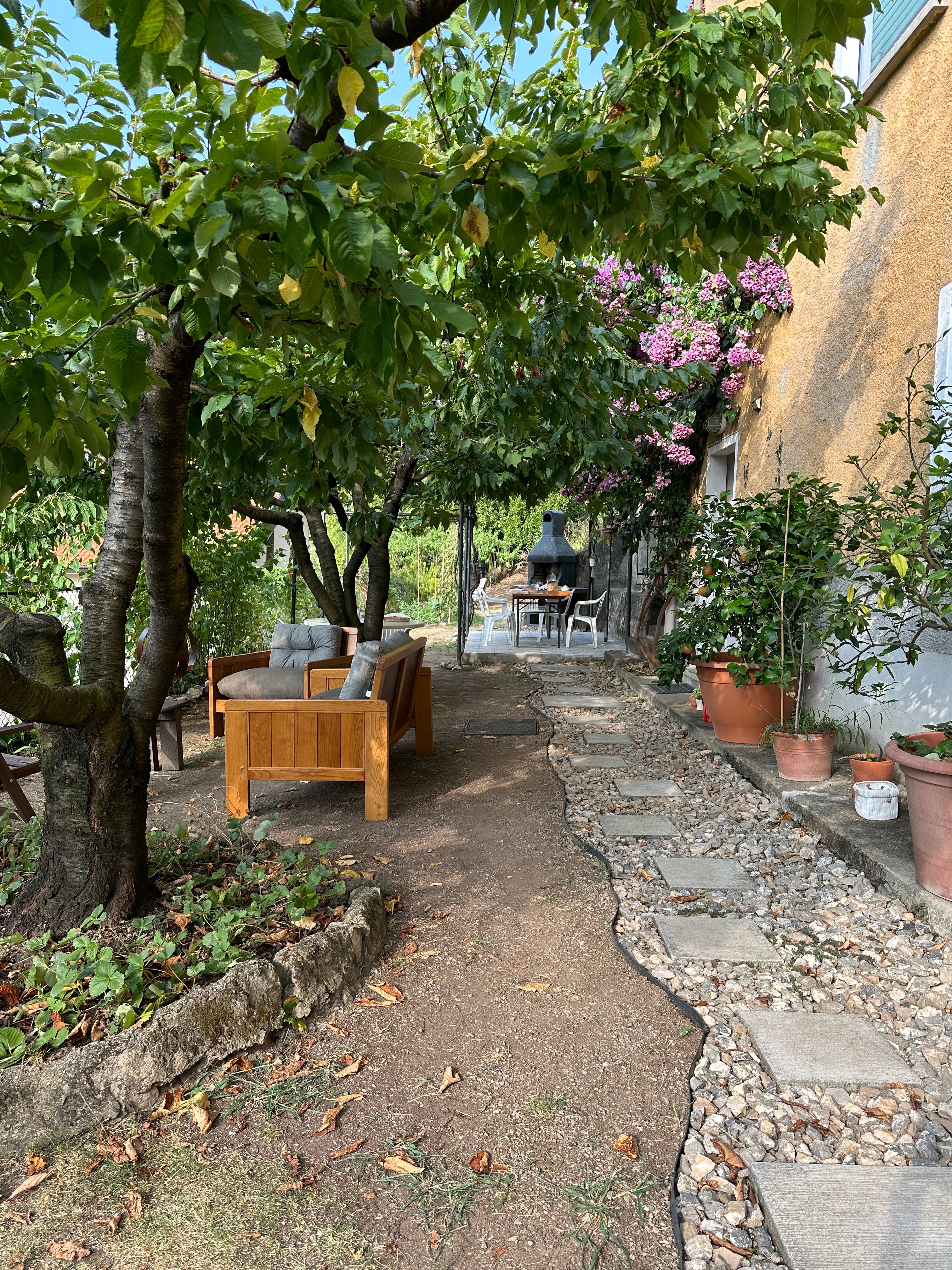 il giardino davanti alla casa con vialetto con sassolini, piante e salottino