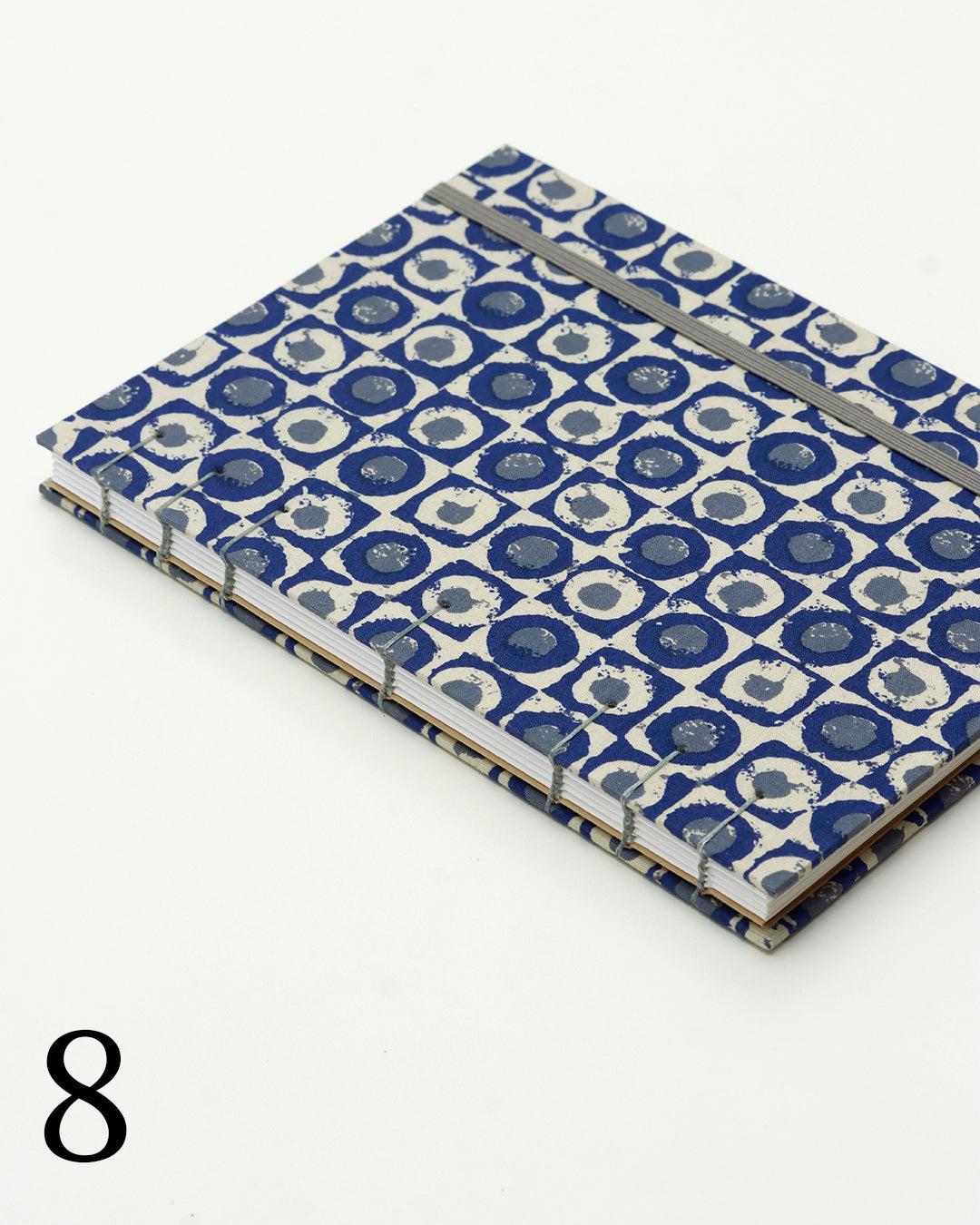 Quaderno per calligrafia con rilegatura copta, copertina in tessuto a motivo geometrico con cerchi concentrici blu navy e crema, elastico e filo grigio