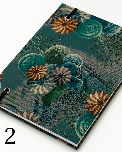 Quaderno per calligrafia con rilegatura copta, copertina in tessuto stampato con conchiglie e ricci di mare stile tavola naturalistica ottocentesca su fondo verde petrolio, elastico e filo golden brown