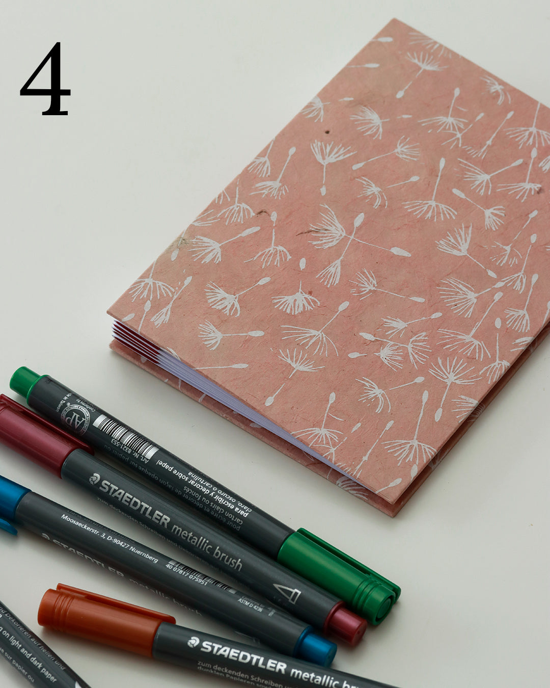 Quaderno per hand lettering con rilegatura australiana, copertina in carta di lokta color terracotta con motivo di semi di tarassaco, dorso a fisarmonica rosso