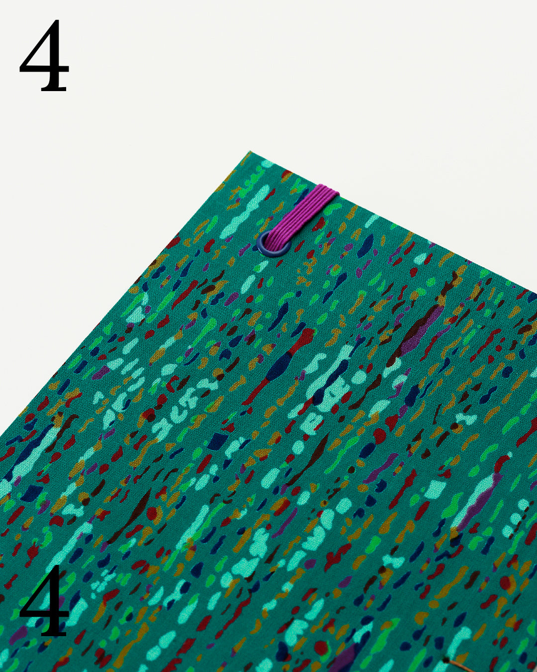Quaderno per calligrafia con rilegatura copta, copertina in tessuto verde smeraldo con trattini e macchioline multicolore, elastico viola, occhielli blu, filo golden brown